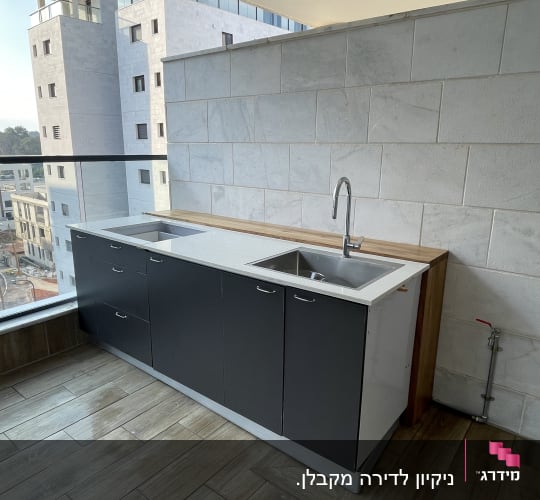 כיור נירוסטה עם ברז על משטח עבודה